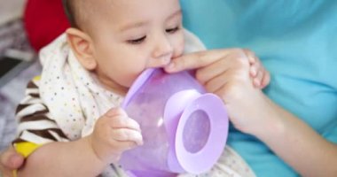 Anne bebeği kollarında tutuyor ve oğlunu kaşıkla besliyor. aile, yemek, çocuk, yeme ve ebeveynlik kavramı