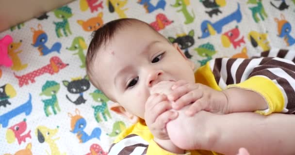 Spädbarn, barndomskoncept - närbild av leende glad baby leker med en teeter. Tänderna avskurna. De första tänderna. Glädje tandlös 7 månader baby bita, gnager teeter leksak — Stockvideo