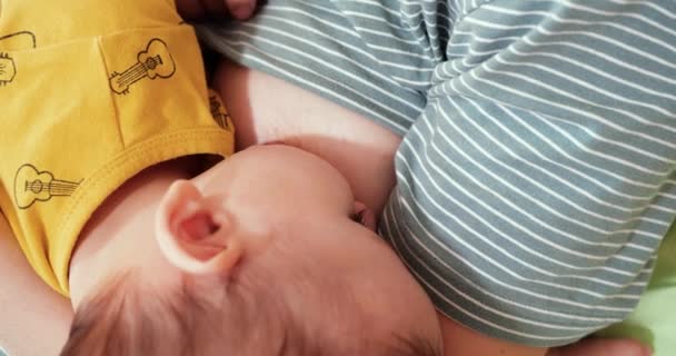 Moeder die haar pasgeboren baby borstvoeding geeft op de bank. Melk van moeders borst is een natuurlijk medicijn voor de baby. familie, voedsel, kind, eten en ouderschap concept — Stockvideo