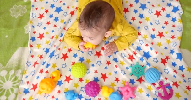 Spädbarn, barndomskoncept - närbild av leende glad baby leker med en teeter. Tänderna avskurna. De första tänderna. Glädje tandlös 7 månader baby bita, gnager teeter leksak — Stockvideo