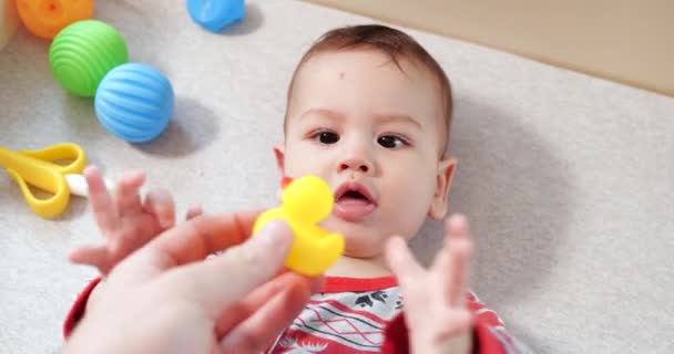 Säugling, Kindheitskonzept - Nahaufnahme eines lächelnden glücklichen Babys, das mit einem Beißring spielt. Zähne zusammenbeißen. Erste Zähne. Joy zahnlos 7 Monate Baby-Biss, nagt Beißspielzeug — Stockvideo