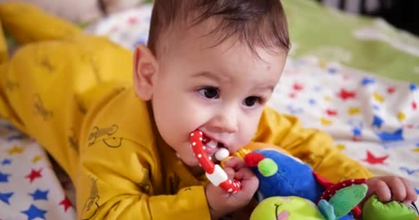 Младенческая, детская концепция - крупным планом улыбающийся счастливый ребенок играет с зубами. Вырезание зубов. Первые зубы. Беззубик Радость 7 месяцев укус ребенка, грызет режущую игрушку — стоковое видео