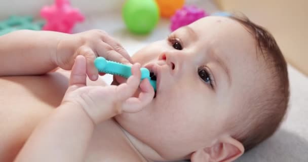 Bebé, concepto de la infancia - primer plano de sonreír feliz Bebé juega con un mordedor. Cortar los dientes. Primeros dientes. Joy mordida de bebé sin dientes de 7 meses, roe el juguete del mordedor — Vídeo de stock