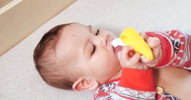 Criança, conceito de infância - close-up de sorrir feliz bebê brinca com um teether. Corte dos dentes. Os primeiros dentes. Joy toothless 7 meses bebê mordida, rói brinquedo teether — Vídeo de Stock