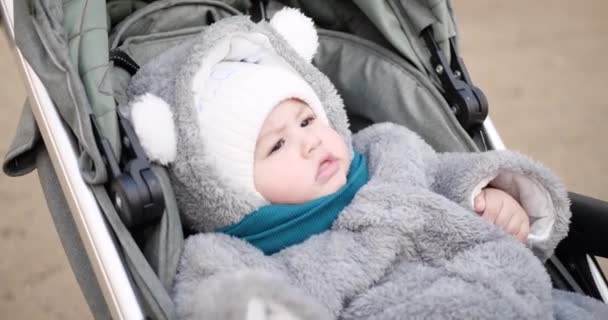 Baby jongen rijdt in een kinderwagen in de winter bij zonnig weer. kleine jongen in koets — Stockvideo