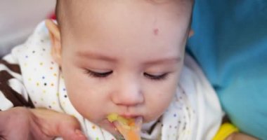 Anne bebeği kollarında tutuyor ve oğlunu kaşıkla besliyor. aile, yemek, çocuk, yeme ve ebeveynlik kavramı