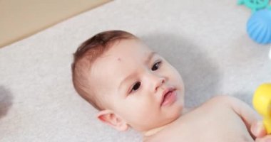 Bebek, çocukluk konsepti. Gülümseyen mutlu bebeğin ip ile oynadığı yakın plan. Diş kesimi. İlk dişler. Neşesiz dişsiz 7 ay bebek ısırığı, kemiren oyuncak