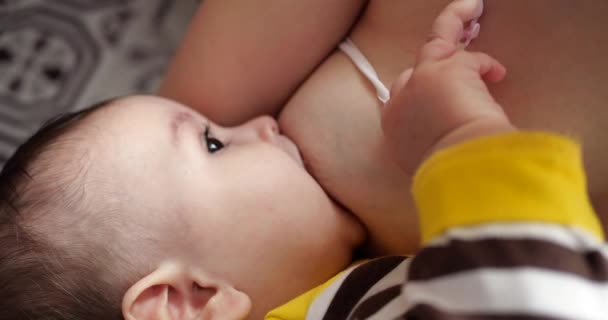 Matka kojit své novorozeně dítě na pohovce. Mléko z prsou matky je přirozený lék pro dítě. rodina, jídlo, dítě, stravování a rodičovství koncept — Stock video