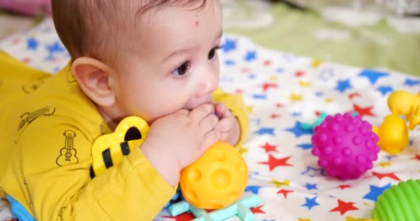 Säugling, Kindheitskonzept - Nahaufnahme eines lächelnden glücklichen Babys, das mit einem Beißring spielt. Zähne zusammenbeißen. Erste Zähne. Joy zahnlos 7 Monate Baby-Biss, nagt Beißspielzeug — Stockvideo