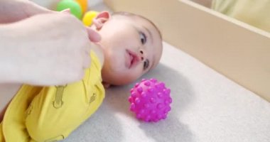 Annem küçük bir çocuğu yatakta giydirir. Tıp, sağlık, aile, masumiyet, pediatri, mutluluk bebek kavramları