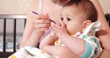 Anne bebeği kollarında tutuyor ve oğlunu kaşıkla besliyor. aile, yemek, çocuk, yeme ve ebeveynlik kavramı