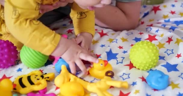 Una giovane madre siede sul letto con un bambino piccolo tra le braccia e controlla il gioco con un etere e altri giocattoli tattili. Maternità, maternità e concetto di famiglia — Video Stock