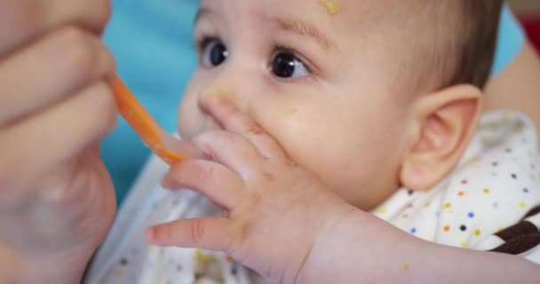 Mamma håller barnet i sina armar och matar sin pojke med en sked. familj, mat, barn, mat och föräldraskap — Stockvideo