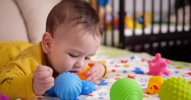 Säugling, Kindheitskonzept - Nahaufnahme eines lächelnden glücklichen Babys, das mit einem Beißring spielt. Zähne zusammenbeißen. Erste Zähne. Joy zahnlos 7 Monate Baby-Biss, nagt Beißspielzeug — Stockvideo