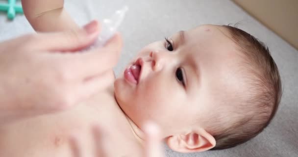 Maman goutte des gouttes de nez au bébé pendant que celui-ci ment et sourit. Nettoyage nez de morve — Video