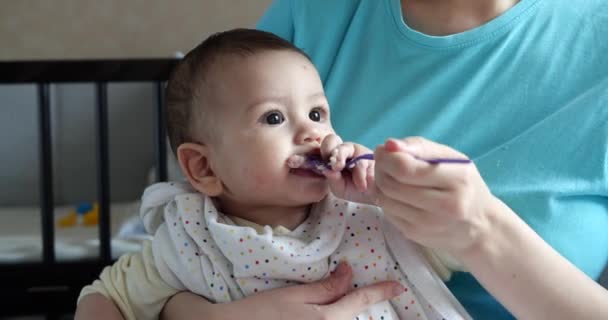 Madre tiene il bambino tra le braccia e lo nutre con un cucchiaio. famiglia, cibo, bambino, mangiare e concetto di genitorialità — Video Stock