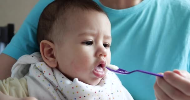 Madre tiene il bambino tra le braccia e lo nutre con un cucchiaio. famiglia, cibo, bambino, mangiare e concetto di genitorialità — Video Stock