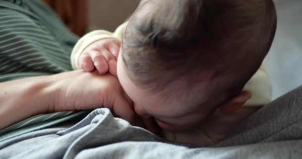 En ung mor håller i en vacker sjumånaders son som ler och gnager på fingrar och mödrar. kliande tänder hos en nyfödd, barnsjukdomar — Stockvideo