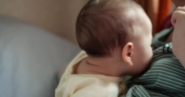 Genç bir anne, yedi aylık güzel bir oğlunu kucağında tutuyor. Gülümseyen ve annesinin elini kemiriyor. Yeni doğmuş bir bebeğin dişleri kaşındırıyor. — Stok video