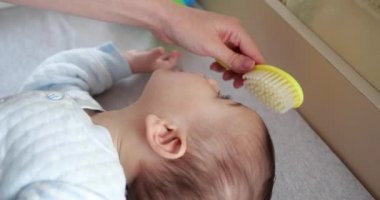 Anne uyanır uyanmaz yeni doğmuş bebeğinin kafasındaki minik kılları tarıyor.