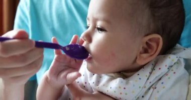 Anne bebeği kollarında tutuyor ve oğlunu kaşıkla besliyor. aile, yemek, çocuk, yeme ve ebeveynlik kavramı