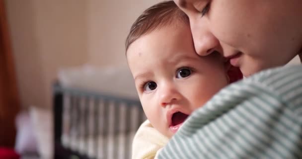 En ung mor håller i en vacker sjumånaders son som ler och gnager på fingrar och mödrar. kliande tänder hos en nyfödd, barnsjukdomar. slow motion — Stockvideo