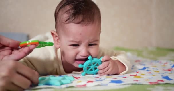 Spädbarn, barndomskoncept - närbild av gråt Baby leker med en teeter. Tänderna avskurna. De första tänderna. Glädje tandlös 7 månader baby bita, gnager teeter leksak — Stockvideo