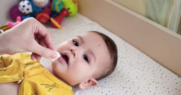 Primo piano del viso di pulizia della madre e degli occhi del suo neonato con cooton pad. La mamma sta pulendo il bambino con un batuffolo di cotone bagnato. rallentatore — Video Stock