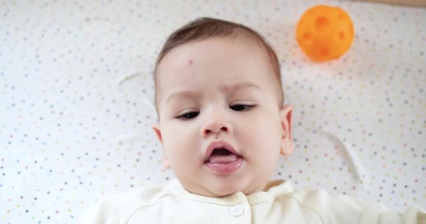 Niemowlę, koncepcja dzieciństwa - zbliżenie uśmiechniętego szczęśliwego dziecka bawi się gryzakiem. Wycinanie zębów. Pierwsze zęby. Radosny, bezzębny 7-miesięczny kąsek dziecka, gryzie gryzak zabawki. zwolniony ruch — Wideo stockowe