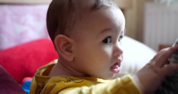 Een jonge moeder houdt een mooie zeven maanden oude zoon vast die glimlacht en knaagt aan vingers en moeders hand. jeukende tanden van een pasgeborene, tandjes. slow motion — Stockvideo