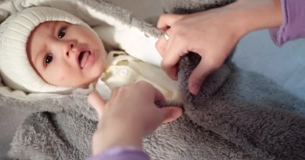 Mamma klär en liten pojke på sängen. Medicin, sjukvård, familj, oskuld, pediatri, lycka spädbarnskoncept. slow motion — Stockvideo