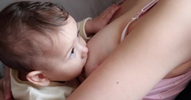 Anne yeni doğmuş bebeğini koltukta emziriyor. Anne sütü bebek için doğal bir ilaçtır. Aile, yemek, çocuk, yeme ve ebeveynlik kavramı. yavaş çekim