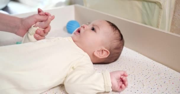 O mamă fericită care ridică un copil îl ajută pe fiu să stea întins în pat acasă. Mama îl învaţă pe băieţel să se aşeze. Mama și copilul se joacă acasă. mișcare lentă — Videoclip de stoc