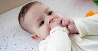 Bebek, çocukluk konsepti. Gülümseyen mutlu bebeğin ip ile oynadığı yakın plan. Diş kesimi. İlk dişler. 7 aylık dişsiz bebek ısırığı, bağcıklı oyuncağı kemiriyor. yavaş çekim