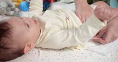 Annem yeni doğmuş bebeğinin bezini bir değişim masasına koyuyor. Bebek bakımı, kadın bebek bezi değiştiriyor. İçeride kundaklama masasında yatıyor. yavaş çekim