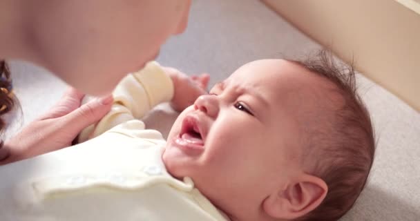 Maman habille un petit garçon qui pleure sur le lit. Médecine, soins de santé, innocence familiale, pédiatrie, bonheur, concepts infantiles. au ralenti — Video