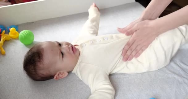 Mor masserar lilla babyn.Baby hudvård och utveckling koncept. Förebyggande av kolik. Kvinnliga händer som masserar magen till nyfödda. slow motion — Stockvideo