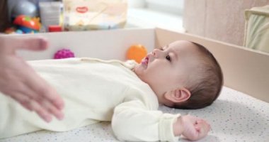Mutlu Anne Kaldıran Bebek Oğlunun Evde Yatağa Yatmasına Yardım Ediyor. Annesi küçük çocuğa oturmasını öğretiyor. Anne ve küçük çocuk evde oynuyorlar. yavaş çekim