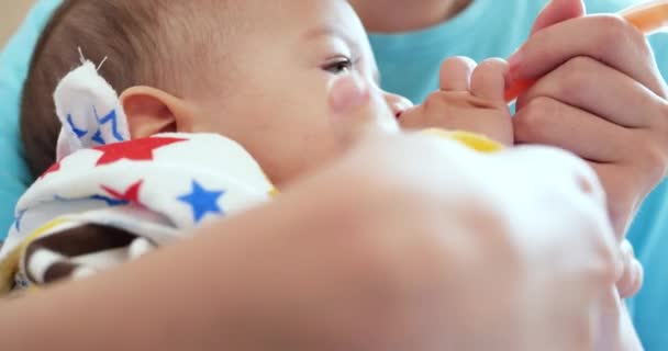 Mãe segura o bebê em seus braços e alimenta seu filho com uma colher. família, alimentação, criança, alimentação e conceito de parentalidade. câmara lenta — Vídeo de Stock