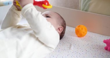 Bebek, çocukluk konsepti. Gülümseyen mutlu bebeğin ip ile oynadığı yakın plan. Diş kesimi. İlk dişler. 7 aylık dişsiz bebek ısırığı, bağcıklı oyuncağı kemiriyor. yavaş çekim