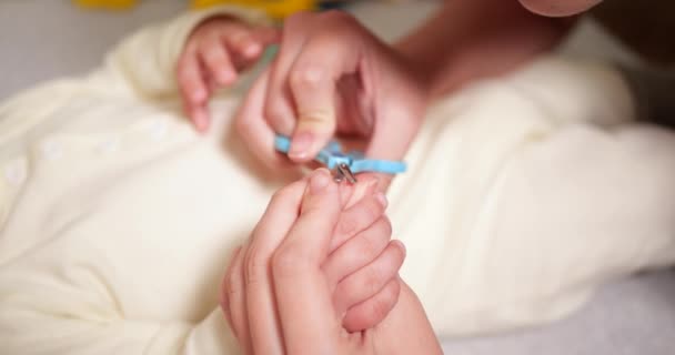 어머니는 손에 있는 작은 아들의 손톱을 베어 냅니다. 한 여자는 작은 아기용 안전 가위를 사용 한다. 느린 동작 — 비디오
