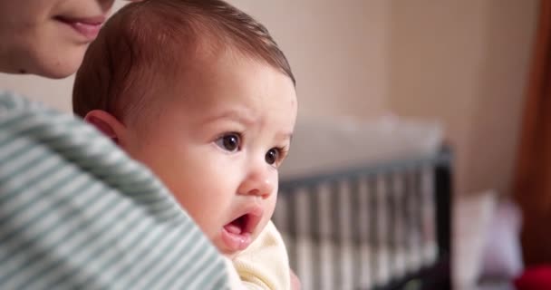 Una giovane madre sta tenendo un bellissimo figlio di sette mesi che sorride e rode le dita e le madri mano. denti pruriginosi di un neonato, dentizione. rallentatore — Video Stock