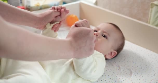 Felice madre sollevamento bambino aiuta figlio sedersi sdraiato sul letto a casa. Mamma insegna al bambino a sedersi. Mamma e bambino che giocano a casa. rallentatore — Video Stock