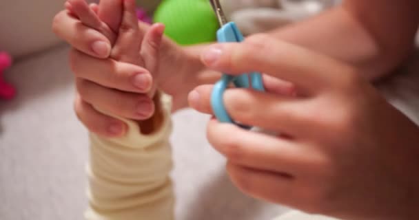 Annesi küçük oğlunun tırnaklarını kesmiş. Bir kadın küçük bebek güvenlik makası kullanır. yavaş çekim — Stok video
