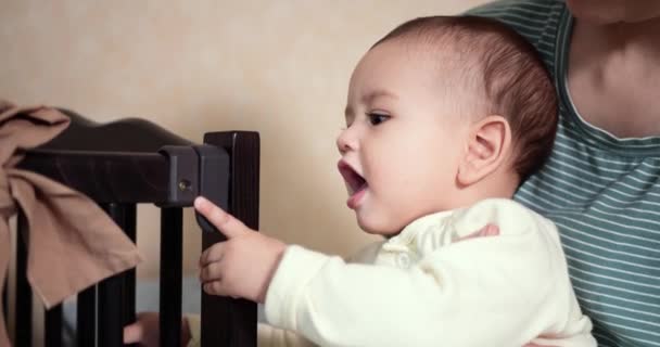 El niño juega con la cuna. Cortando dientes. Primeros dientes. El bebé de 7 meses muerde, roe la esquina de la cama en lugar del mordedor. bebé, concepto de la infancia. cámara lenta — Vídeo de stock