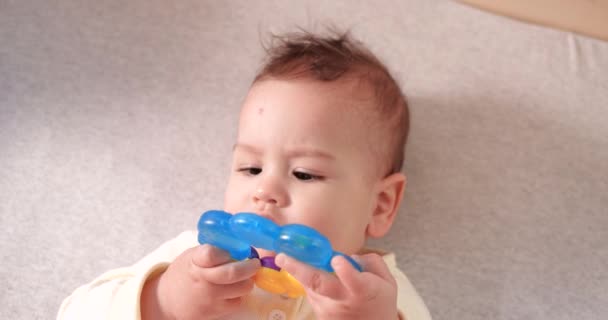 Spädbarn, barndomskoncept - närbild av leende glad baby leker med en teeter. Tänderna avskurna. De första tänderna. Glädje tandlös 7 månaders baby bita, gnager teeter leksak. slow motion — Stockvideo