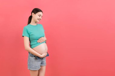 Hamile karnı renkli ve fotokopi alanı var. Açık kotlu müstakbel anne çıplak bebek şişliğini kucaklıyor. Annelik kavramı.