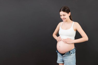 Hamile karnı renkli ve fotokopi alanı var. Açık kotlu bir anne bekliyor. Annelik kavramı.