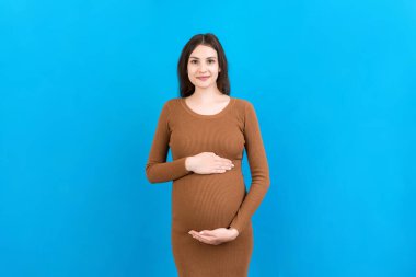 Mutlu hamile kadın renkli arka planda karnına dokunuyor. Müstakbel anne. Bir bebek bekliyorduk. Boşluğu kopyala.