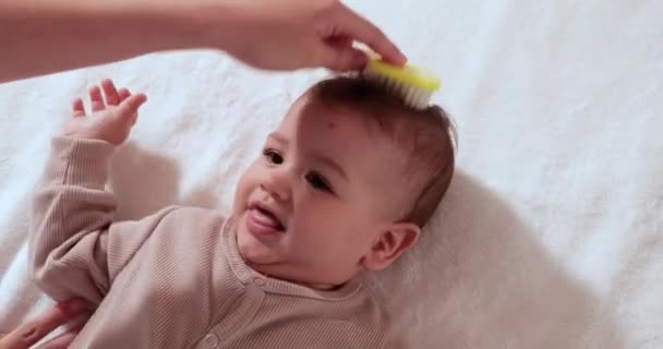 Η μητέρα χτενίζει μικροσκοπικές τρίχες στο νεογέννητο κεφάλι του μωρού της καθώς ξυπνάει. — Αρχείο Βίντεο